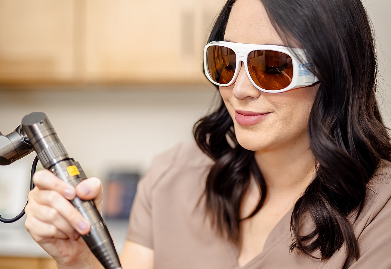 Woman wearing protective glasses, holding medical tool.