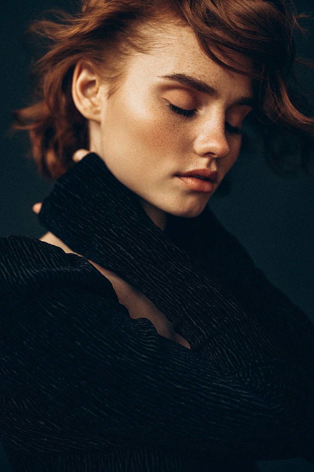Woman with closed eyes in textured black sweater.