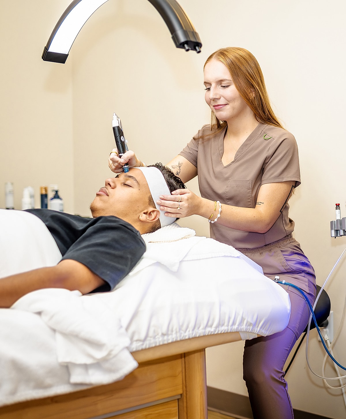 Woman performing skincare treatment on client in clinic.
