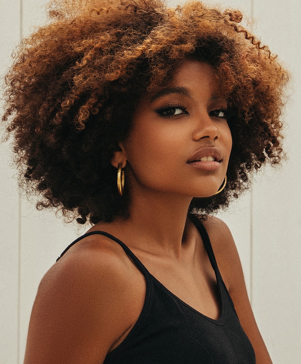 Woman with curly hair wearing hoop earrings.