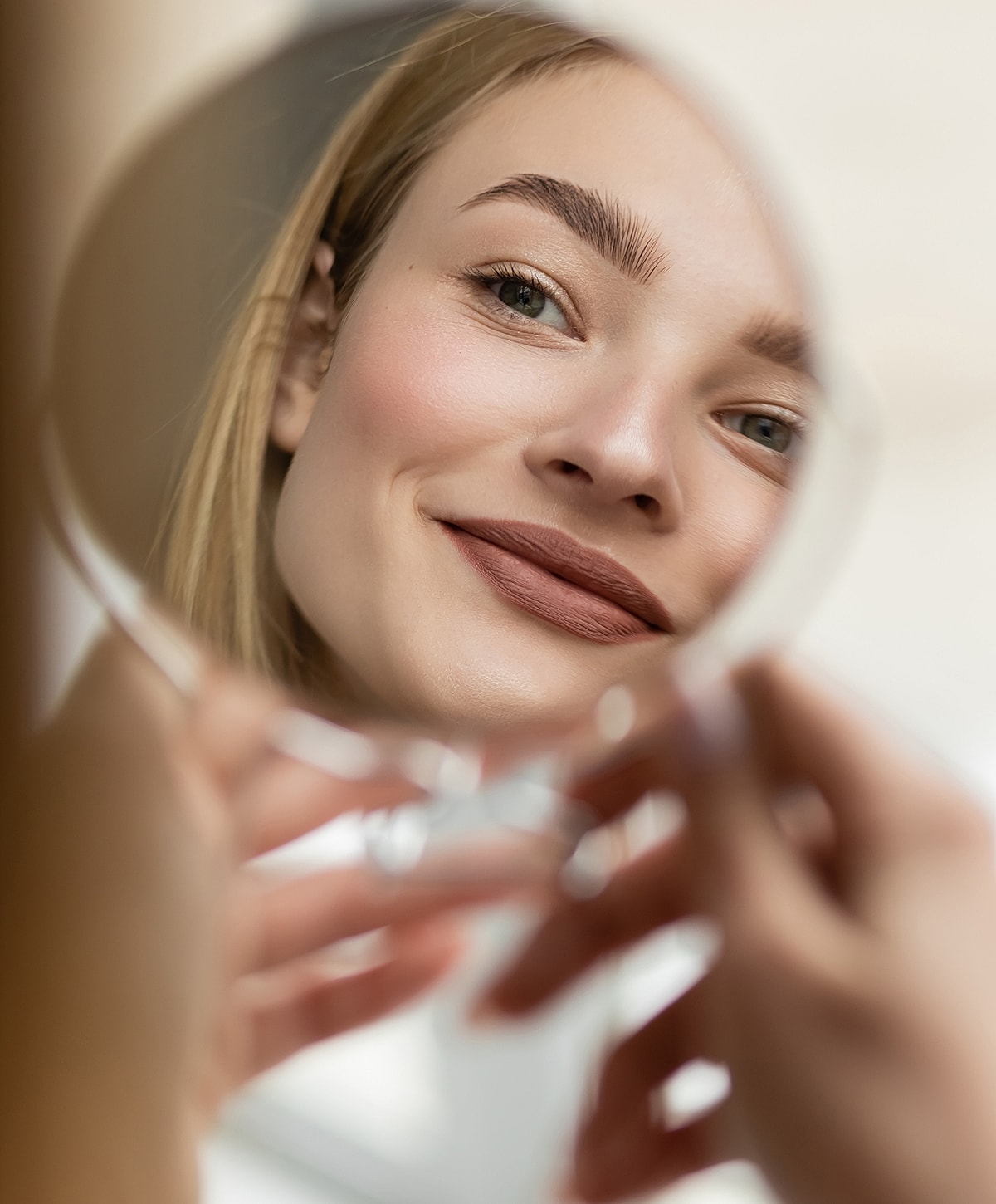 Woman smiling at herself in a mirror.