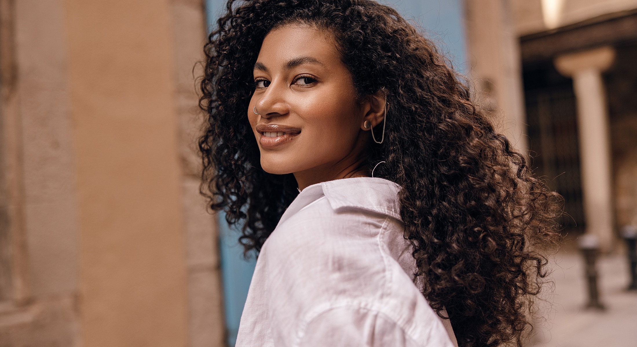 Woman with curly hair smiling outdoors.
