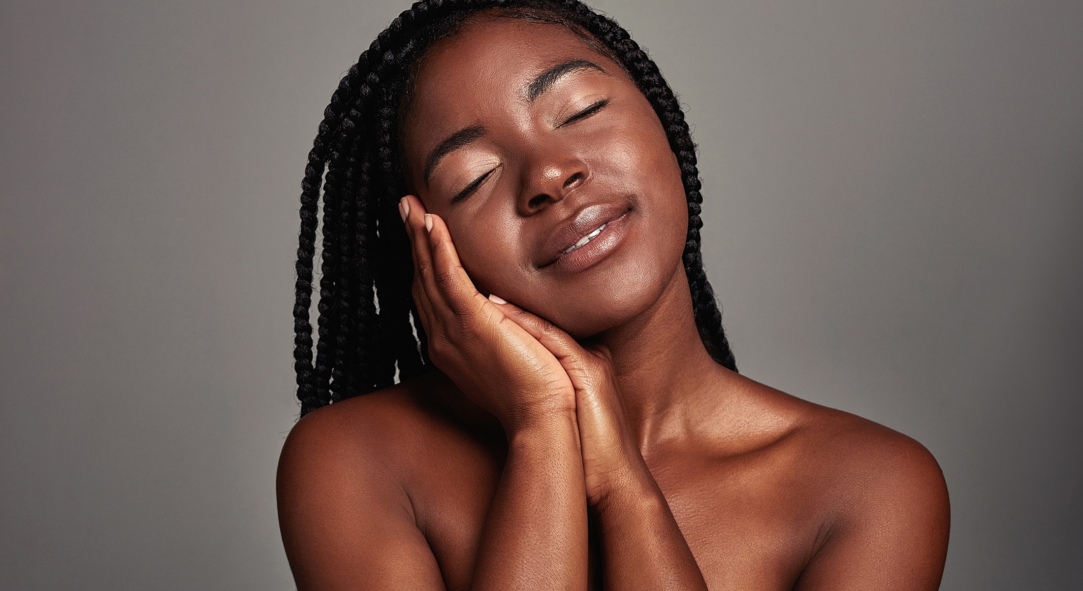 Smiling woman with braided hair, soft lighting.